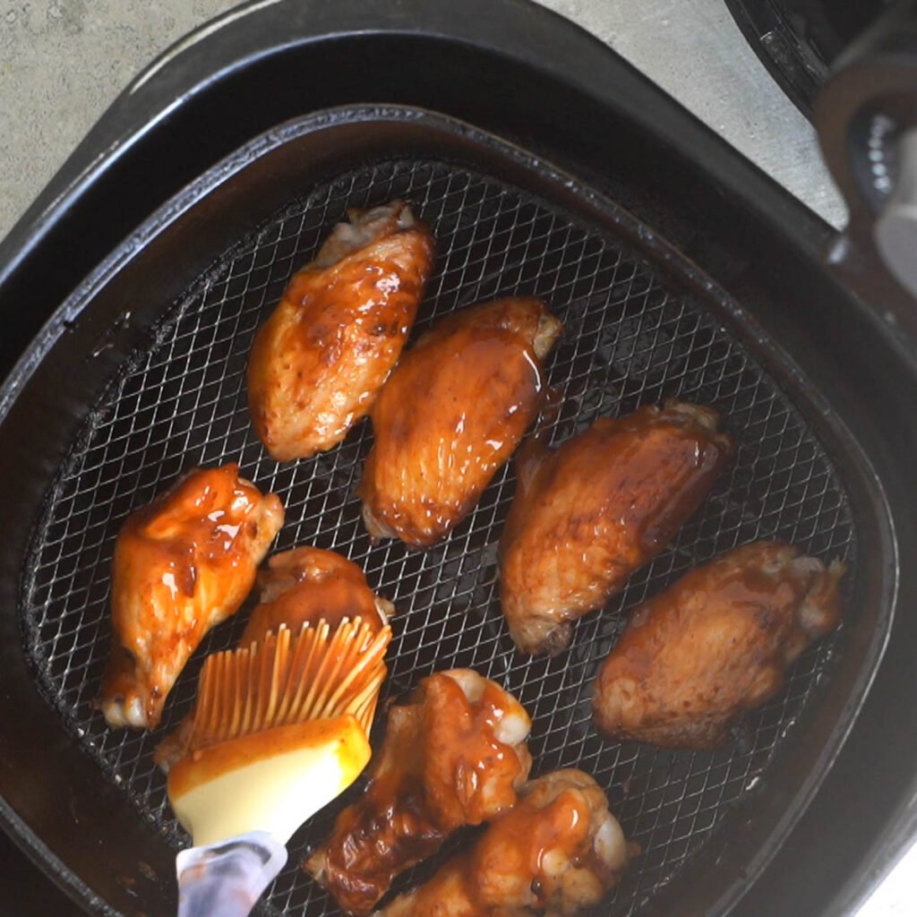 Brushing chicken wings with barbecue sauce