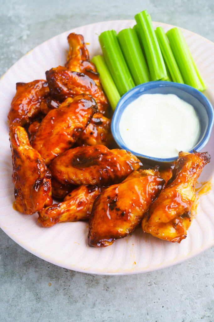 Air fryer BBQ Chicken Wings served in a pink bowl with celery and a blue cheese dip