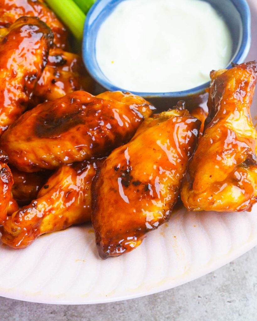 Air fryer BBQ Chicken Wings served in a pink bowl with celery and a blue cheese dip