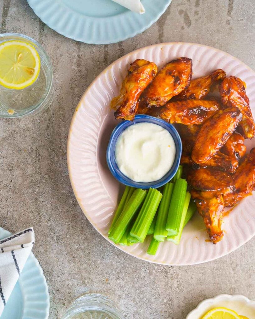 Air fryer BBQ Chicken Wings served in a pink bowl with celery and a blue cheese dip