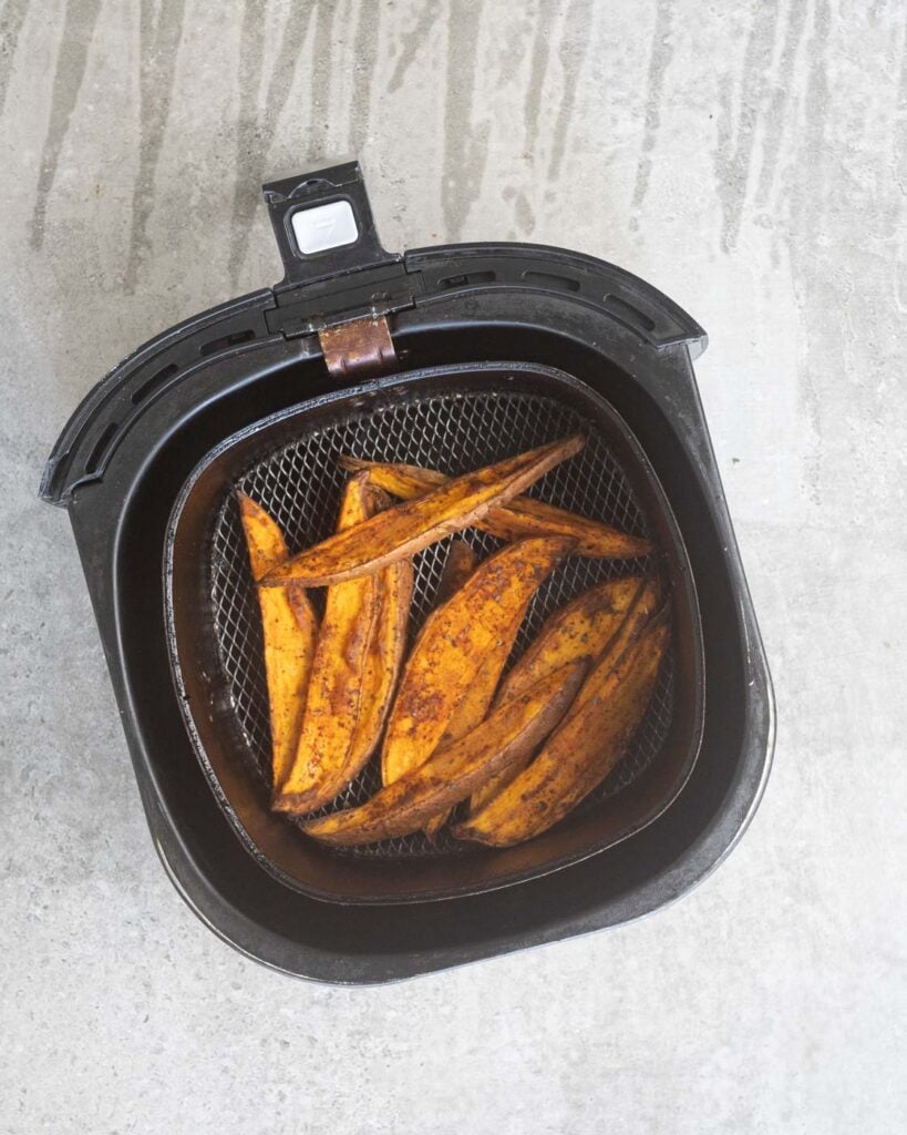 Sweet Potato wedges in the air fryer basket before after being cooked