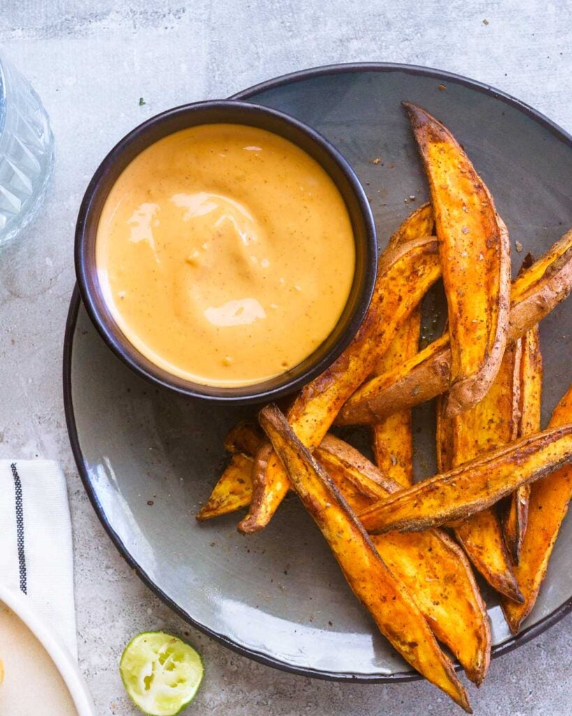 Air fryer Sweet Potato wedges in a grey plate with a sriracha aioli dip