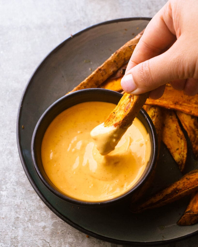 Air fryer Sweet Potato wedges in a grey plate with a sriracha aioli dip