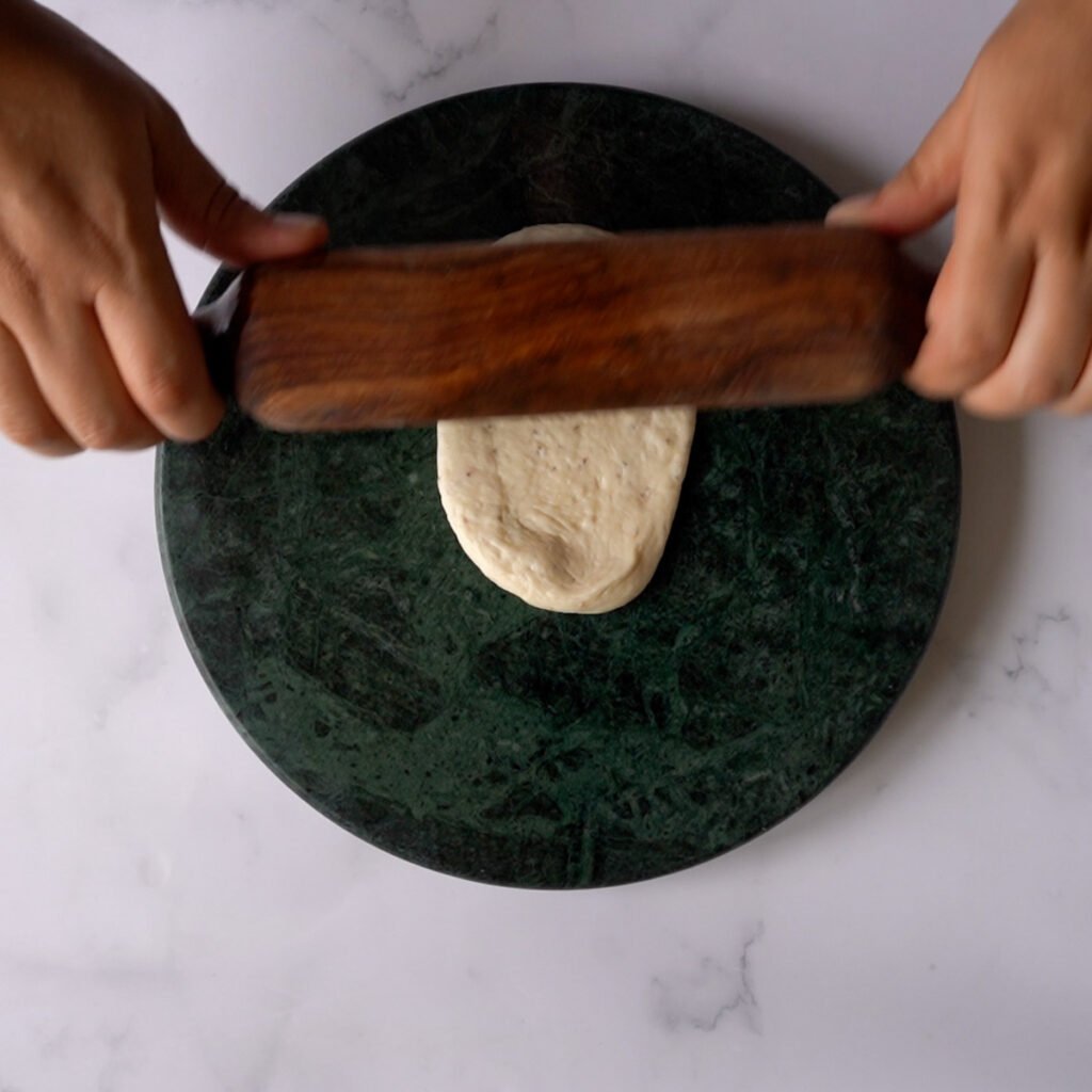 Rolling the bhatura on a green marble rolling surface