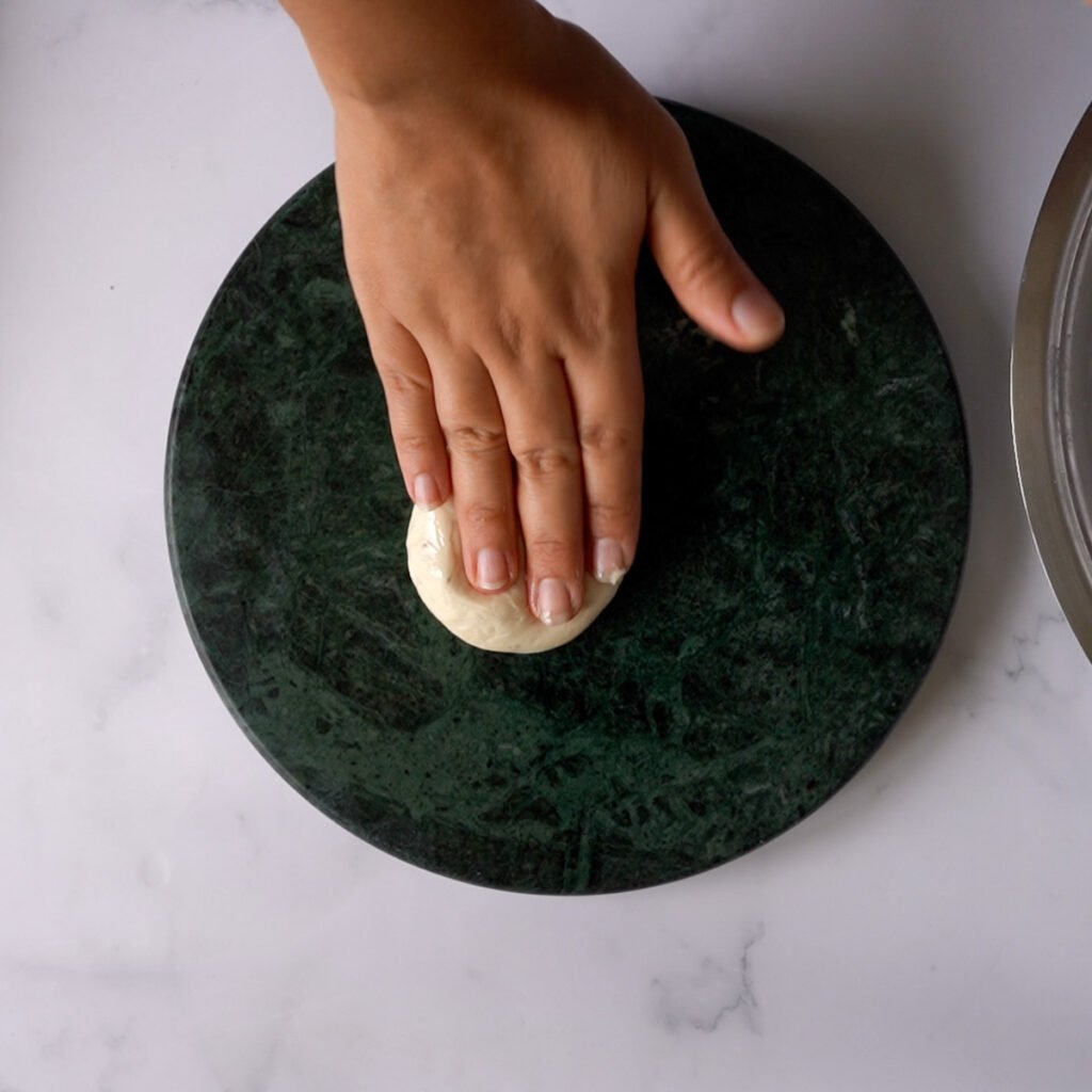 Rolling the bhatura on a green marble rolling surface