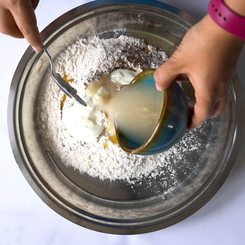 Adding yogurt and activated yeast to make the bhature dough