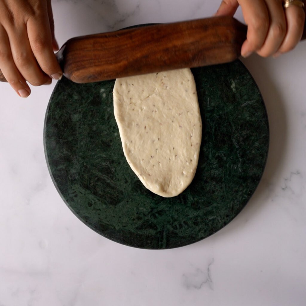 Rolling the bhatura on a green marble rolling surface