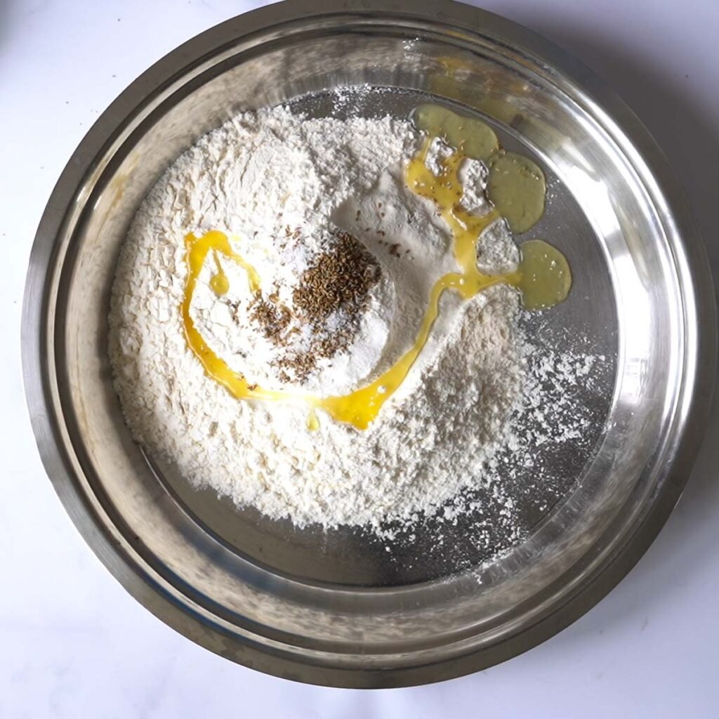 flour, salt.ghee and ajwain in a large platter to make bhature dough