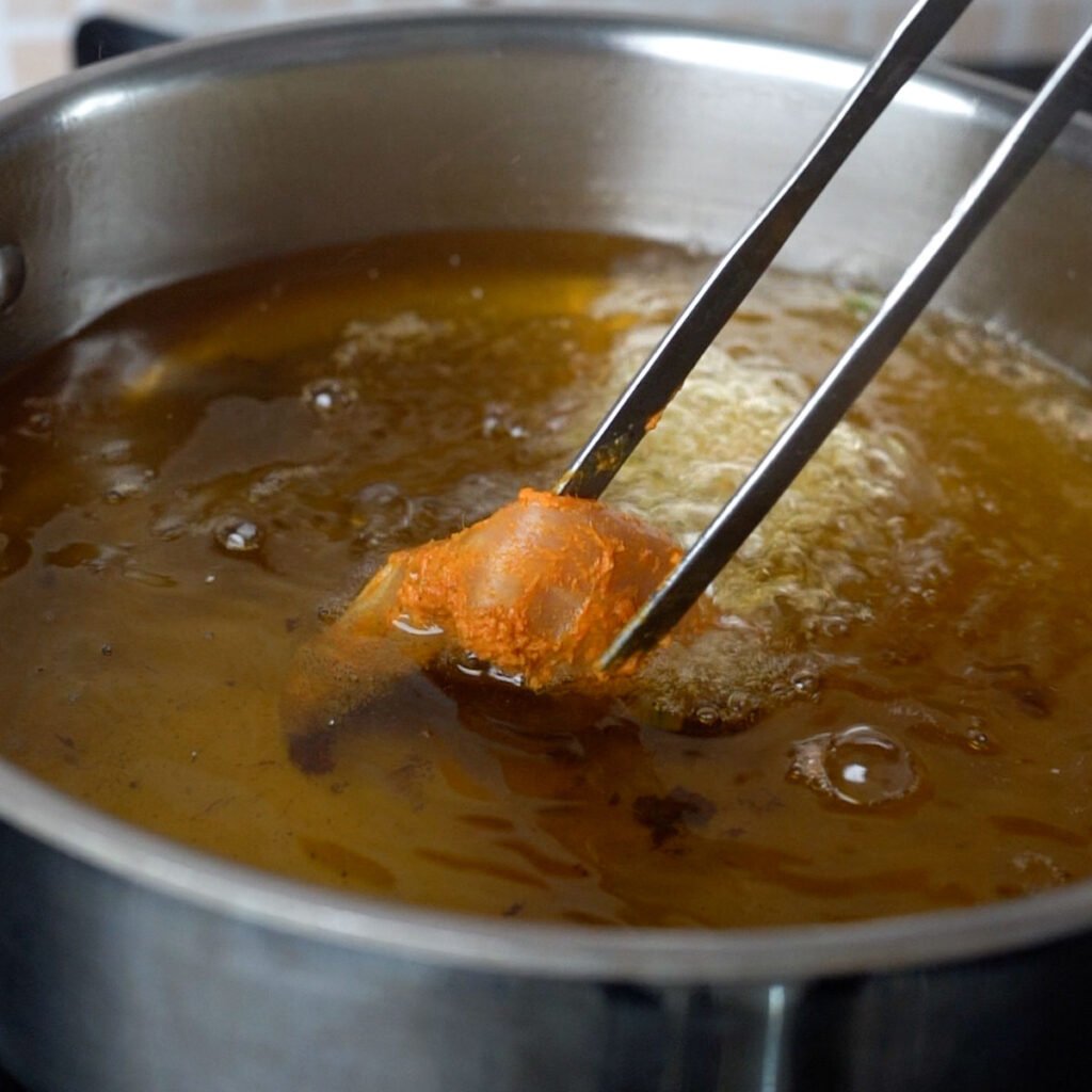 Adding a piece of chicken to the hot oil