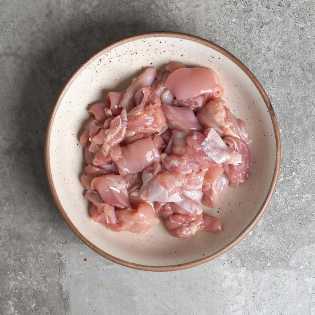 cut pieces of chicken thigh in a white bowl