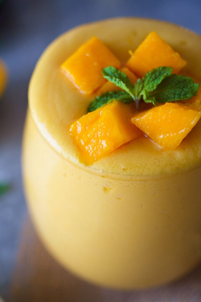 Close up of Mango lassi with cubes of Mango on top along with a sprig of mint