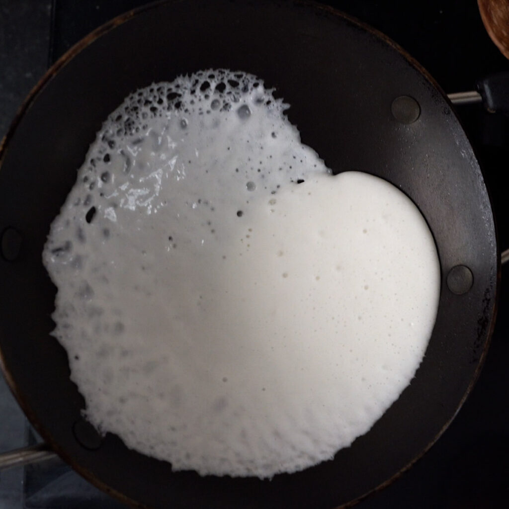 Swirling appam batter in a hot pan