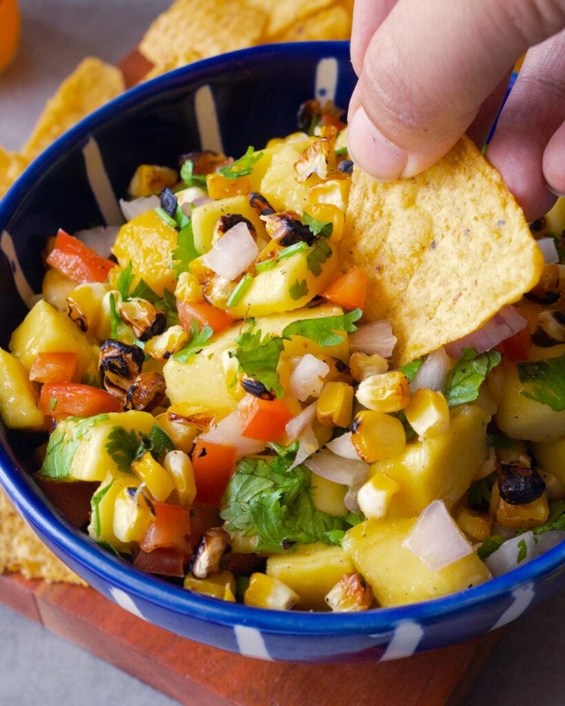 Mango & grilled corn Salsa in a white and blue bowl, served with tortilla chips