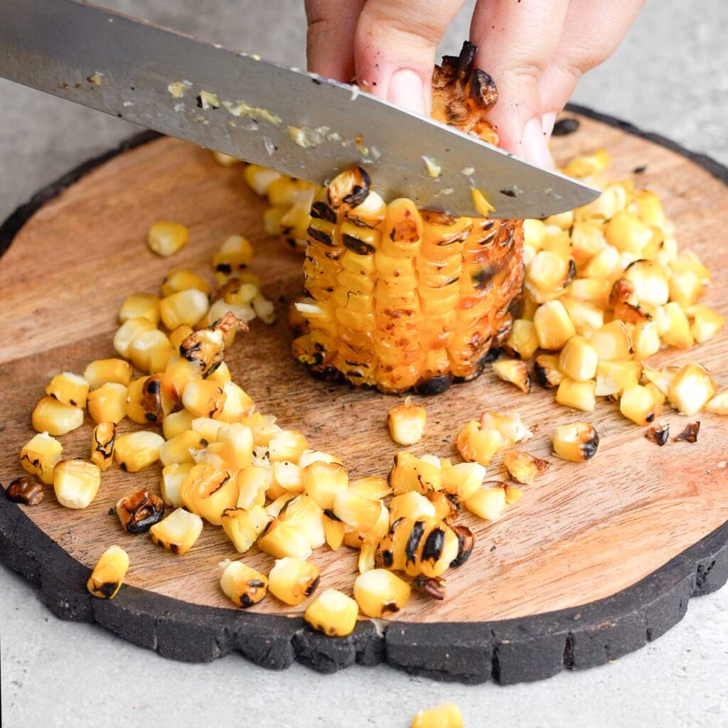Cutting the corn kernals off a grilled corn on the cob
