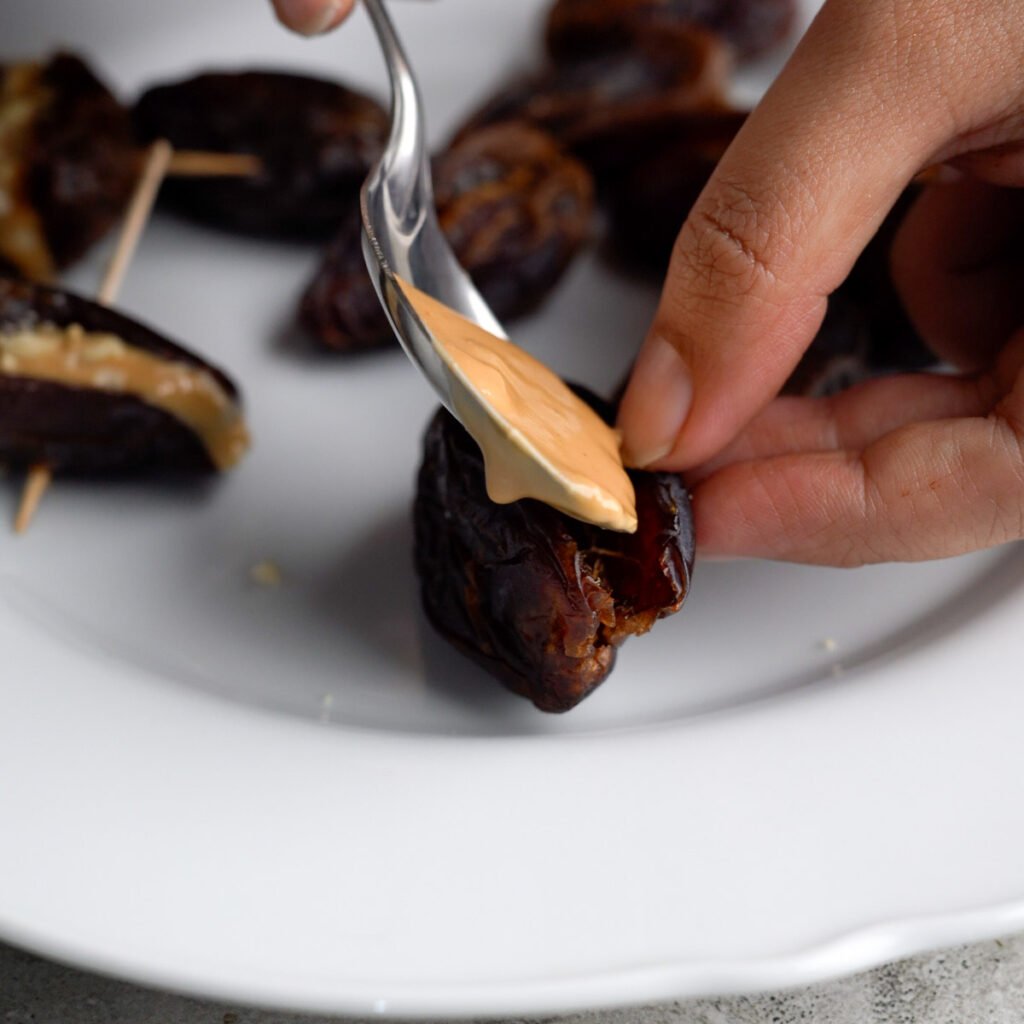 Stuffing the dates with peanut butter using  a spoon