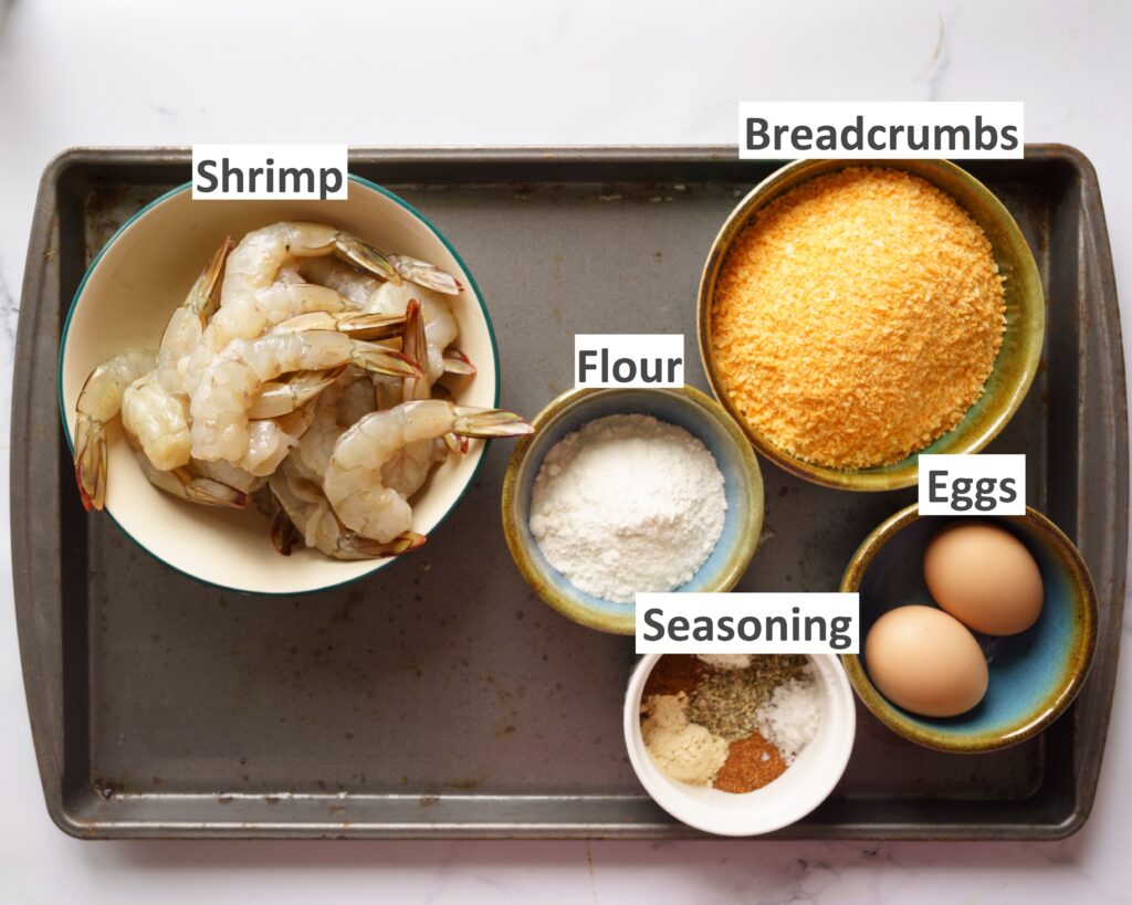 Ingredients needed to make Popcorn shrimp in the air fryer- shrimp, eggs, seasoning, flour, eggs and oil