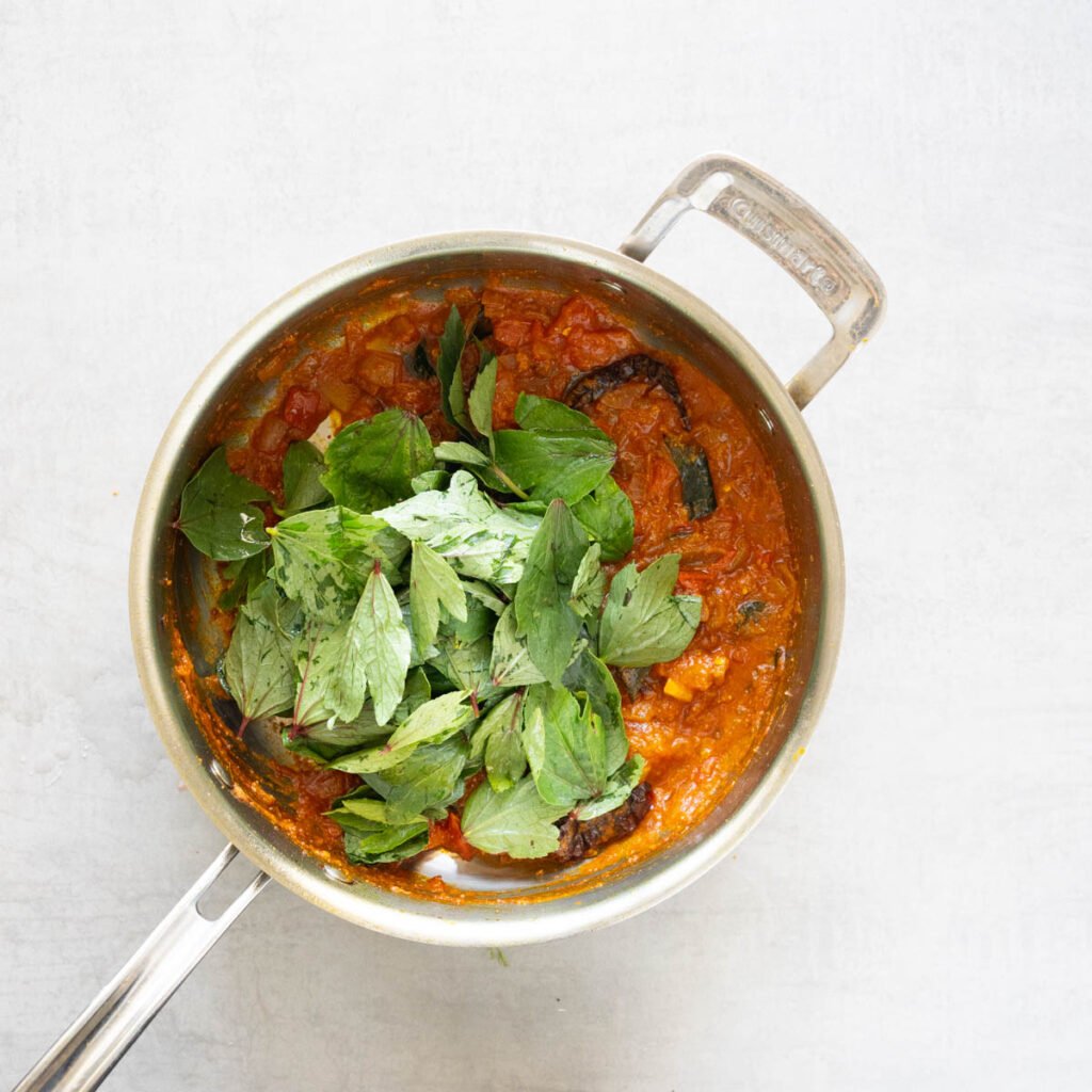 Cuisinart steel pan with onions, tomatoes and spices along with fresh sorrel or gongura leaves