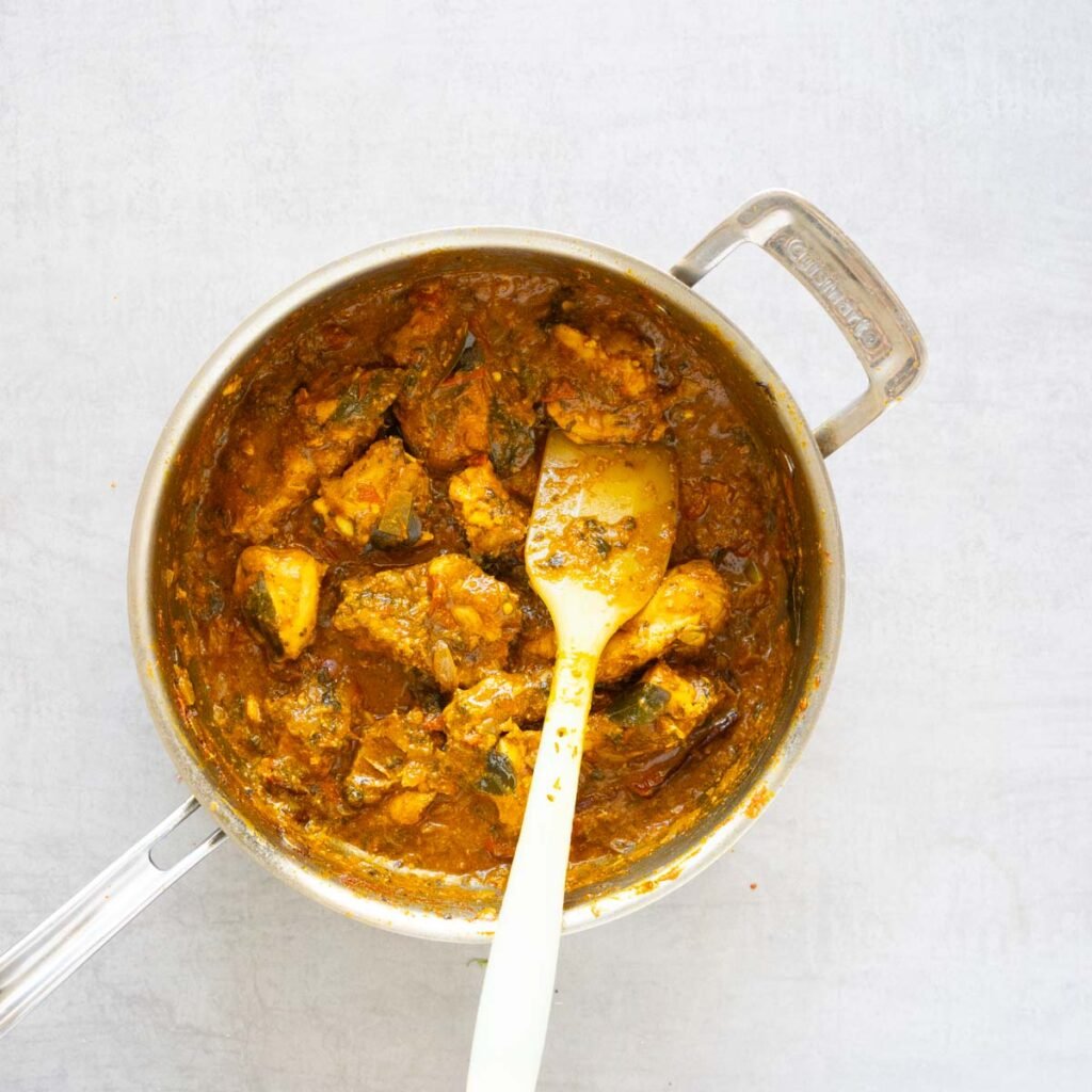 Gongura chicken curry in a steel pan with a rubber spatula