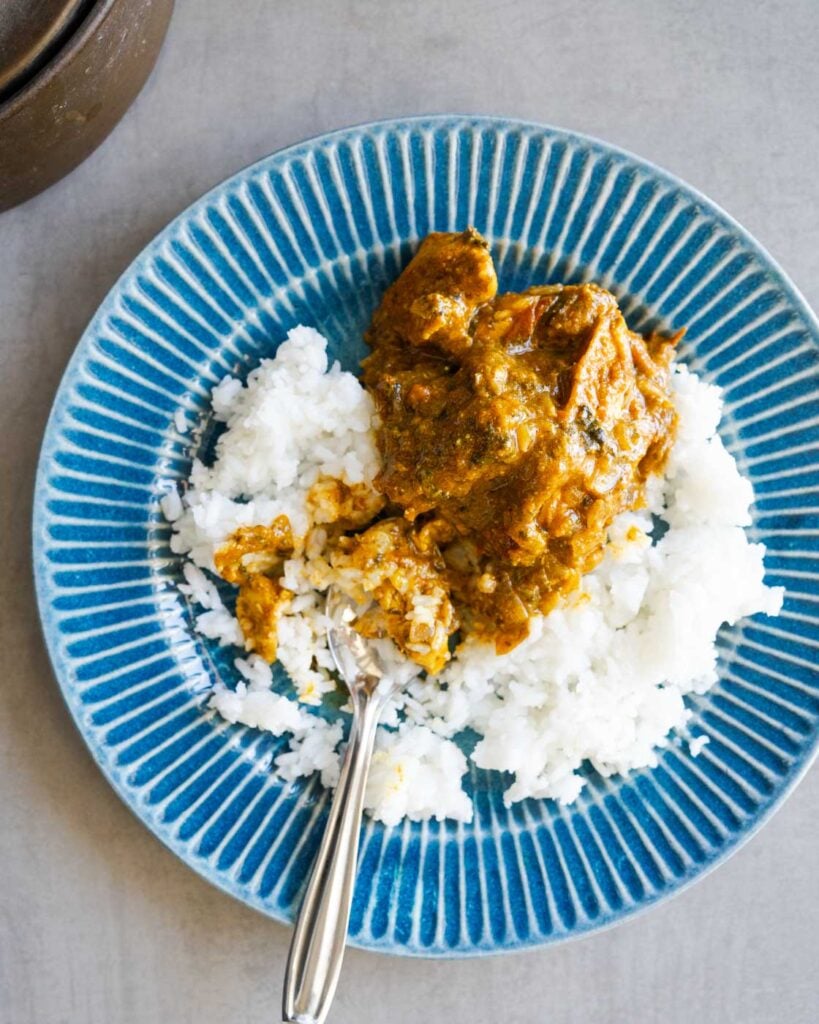 Gongura chicken curry with rice in a blue scalloped plate