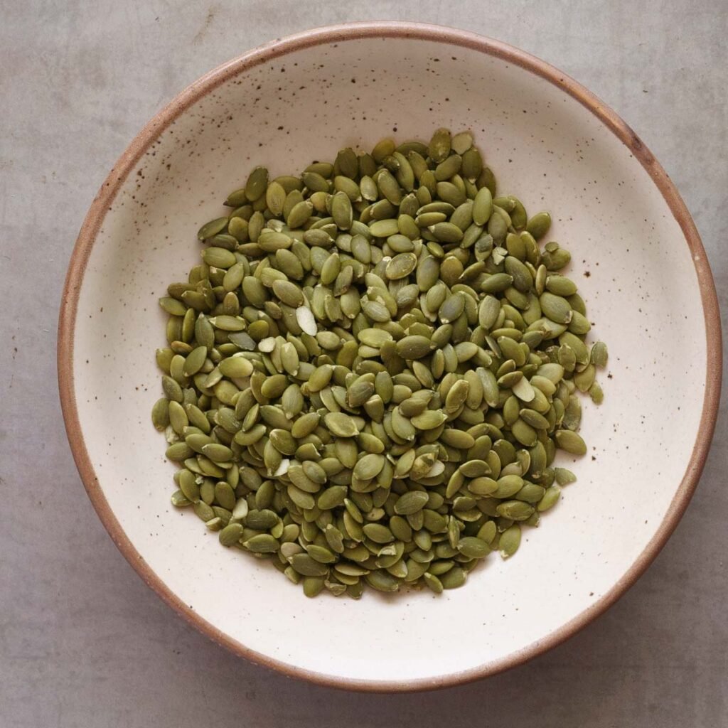 pumpkin seeds or pepitas in a white bowl with brown rim