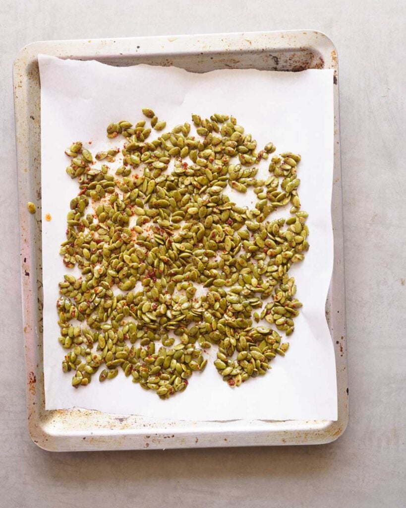 Seasoned pepitas on a baking tray lined with parchment paper