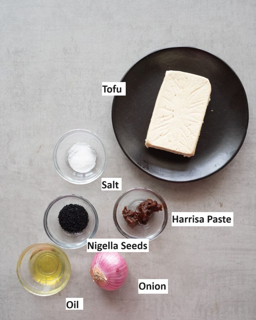 Ingredients needed to make harrissa tofu- a block of tofu, harissa, onion,oil, salt and nigella seeds