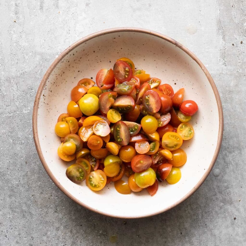Cherry tomatoes quartered in a white bowl