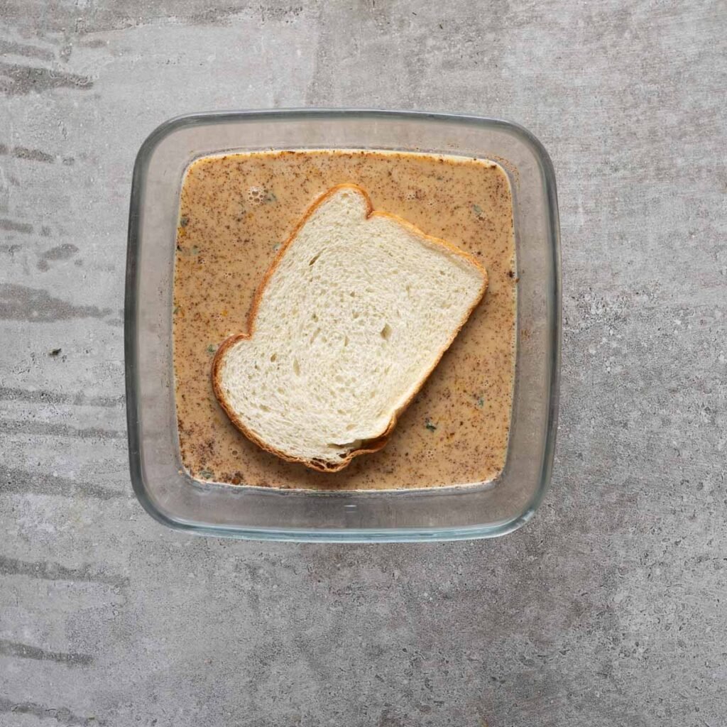 White bread inside a square dish with savory custard