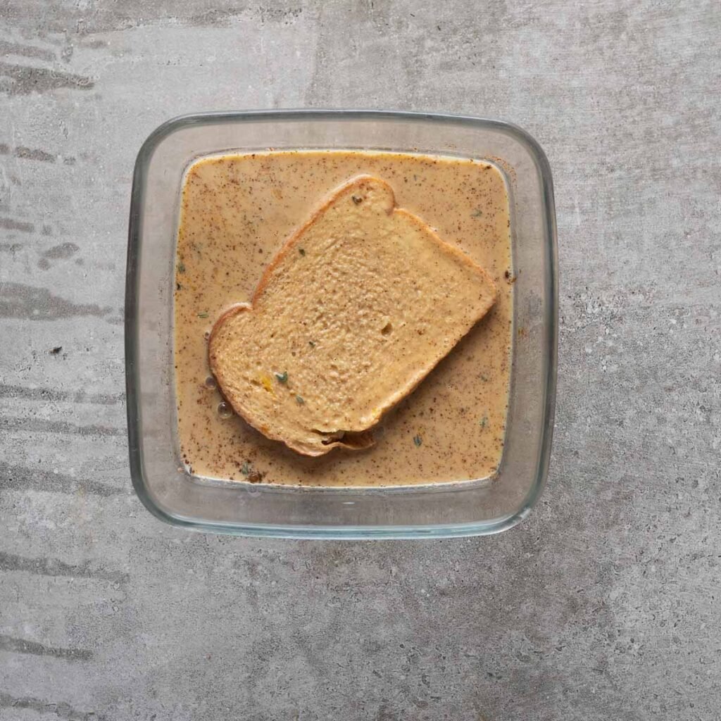 White bread inside a square dish with savory custard