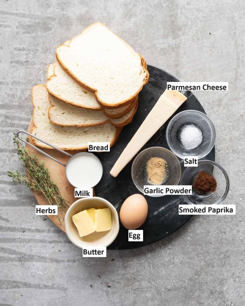 Ingredients needed to make savory french toast - bread, parmesan cheeese, milk, egg, smoked paprika, garlic powder, salt and herbs.