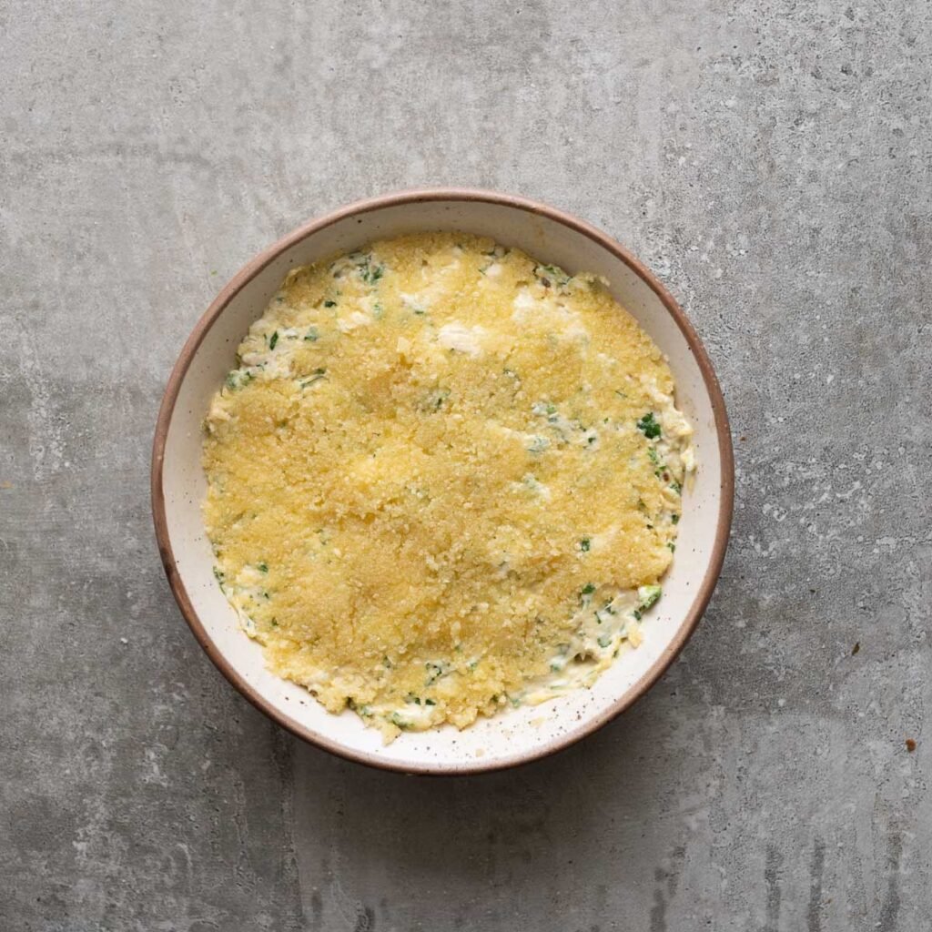 Chicken jalapeno popper mixture inside a baking dish topped with melted butter and breadcurmbs