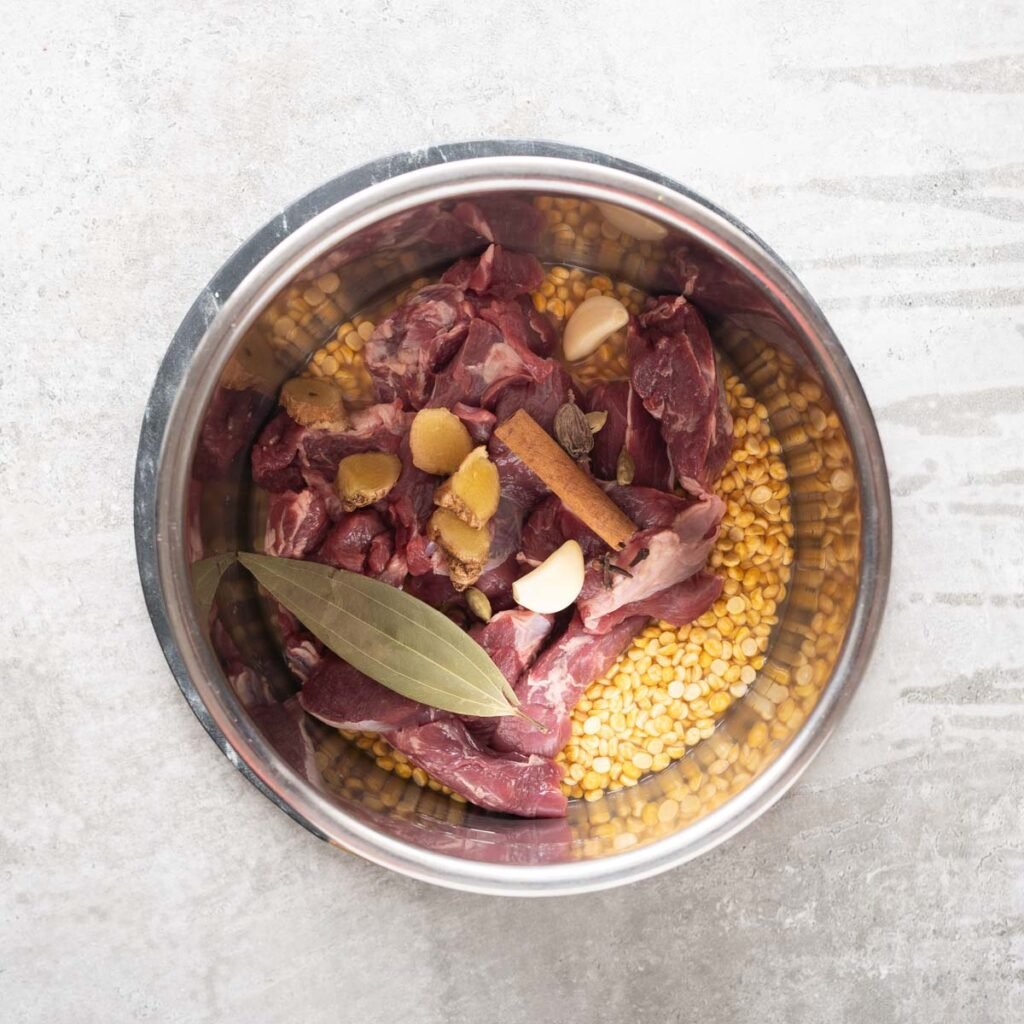 Mutton, ginger, whole spices, garlic and chana dal in a large bowl