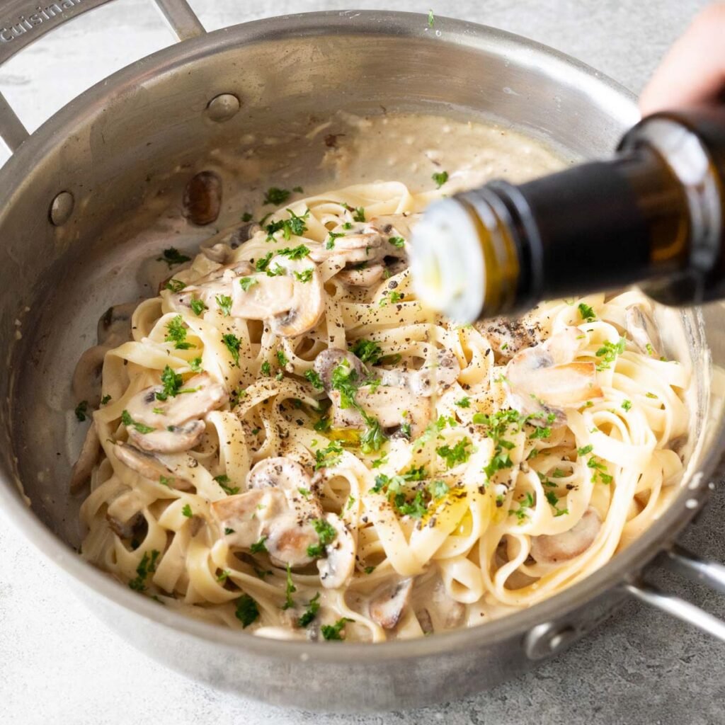 Drizzling truffle oil on mushroom pasta