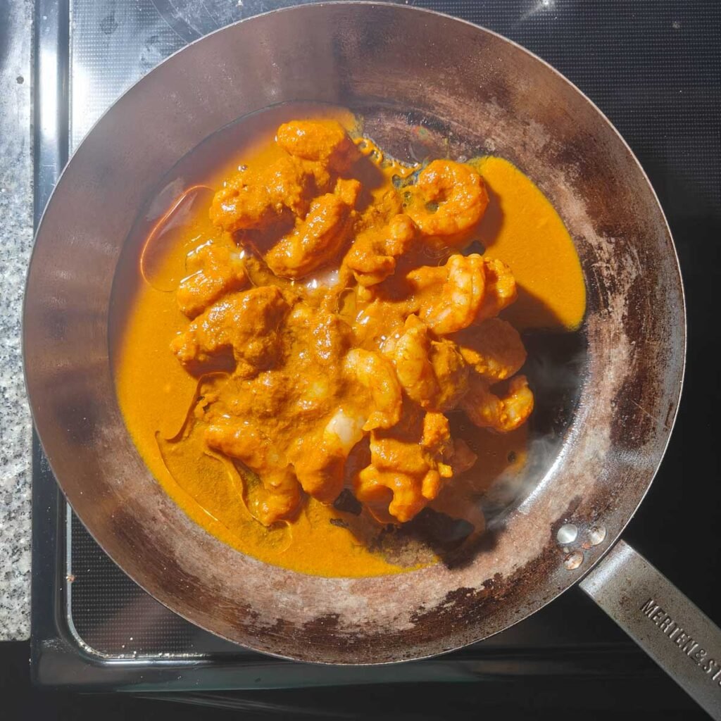 shrimp with oil and marinade in a large black flat pan.