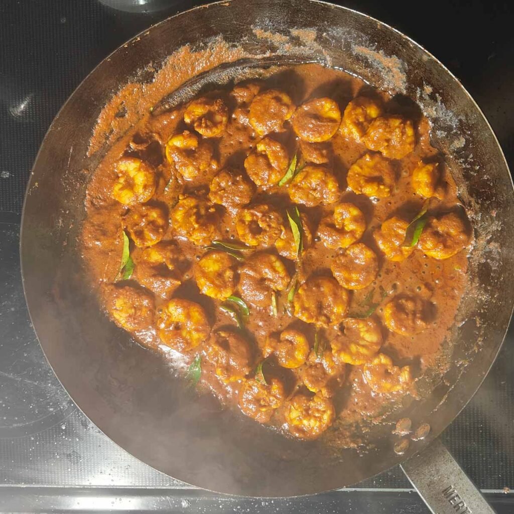 Cooked tawa prawn in a large black carbon steel pan