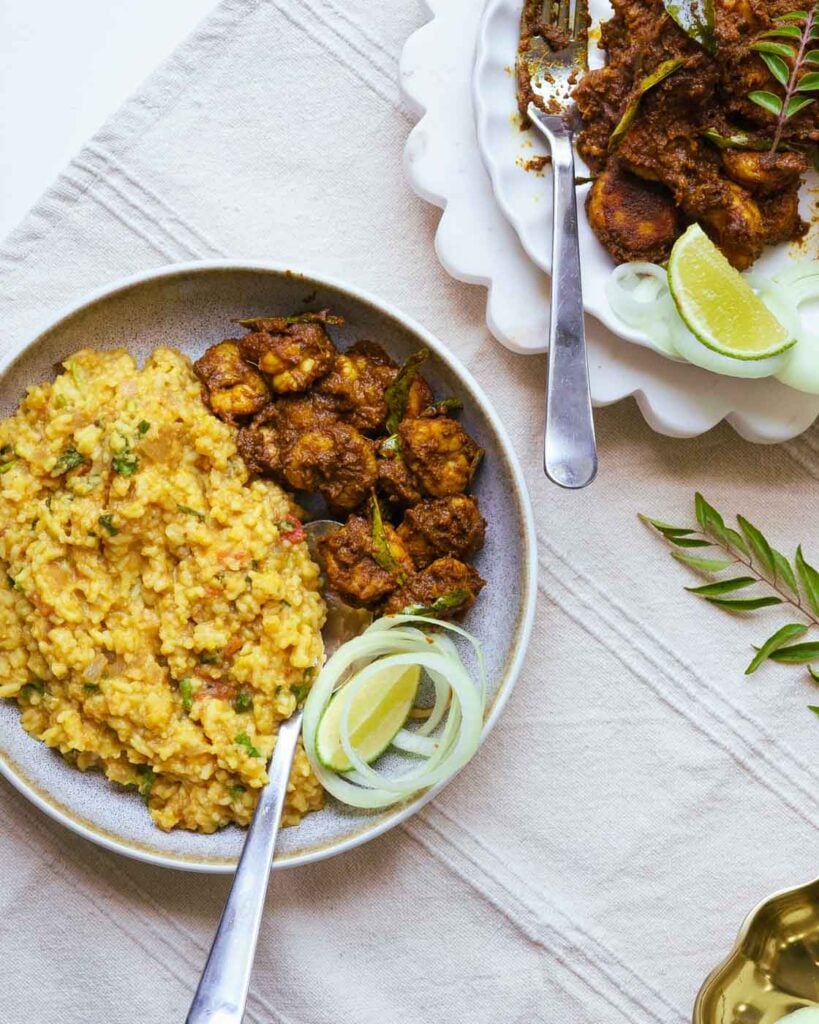 shrimp served with khichdi in a brown bowl along with onions and lemon