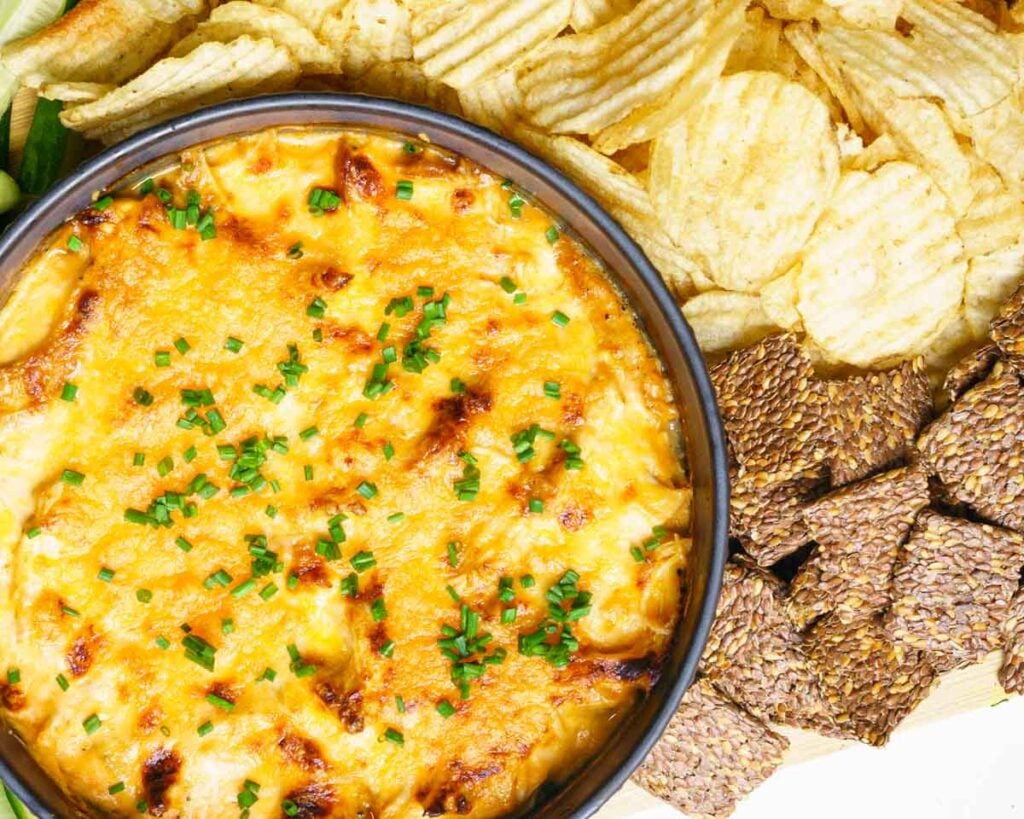 Cottage cheese buffalo chicken dip in a black shallow bowl, served with chips and crackers
